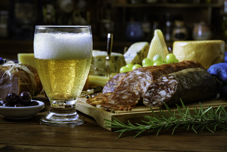 Weihnachtsgeschenke: Unsere Empfehlungen.
Tapas mit Käse, Schinken, Salami, Bier und Chorizo ​​auf einem rustikalen Holztisch