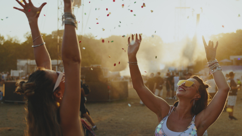 Weihnachtsgeschenke: Unsere Empfehlungen.
Freundinnen vergnügen sich auf einem Musikfestival und werfen Konfetti in die Luft.
