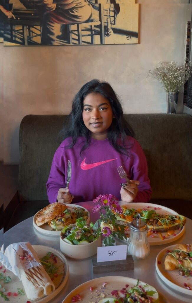 Frau sitzt am Tisch und genießt vegane Gerichte.