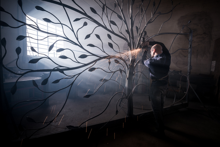 Ein Schmied arbeitet in seiner Schmiede an der Anfertigung eines Torbaums.