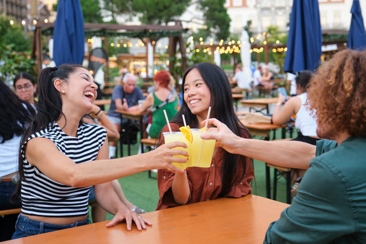 Eine Gruppe junger Menschen sitzt gemütlich in einem Biergarten.