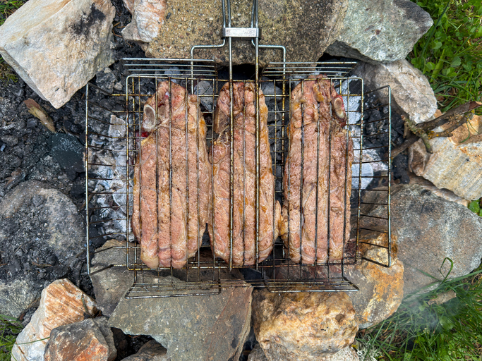 Ein Grillfest im Freien mit auf Holzkohle gegrilltem Fleisch, umrahmt von Steinen.